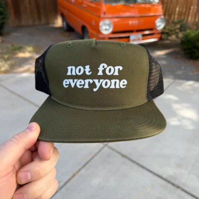 Olive and black mesh trucker hat with white Not for Everyone lettering, front view.